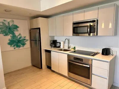 a kitchen with white cabinets and a stainless steel refrigerator at Beach, pool, and Gym 2B 2B Near Gulfstream & Mall in Hallandale Beach