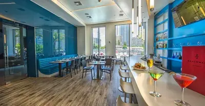 a restaurant with a bar with tables and chairs at Beach, pool, and Gym 2B 2B Near Gulfstream & Mall in Hallandale Beach
