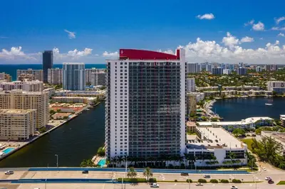 a tall building with a red top on top of it at Ocean views pool gym and more in Hallandale Beach
