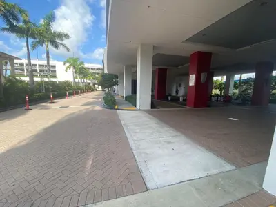 an empty sidewalk next to a building with palm trees at Dream Beach Apt 1BR, Kitchen & Pool Access in Hallandale Beach