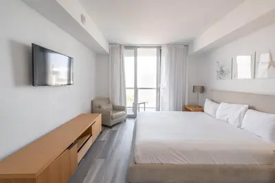a bedroom with a bed and a tv on a wall at 2B 2B Beachfront Pool Gym and Restaurant in Hallandale Beach