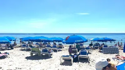 a beach with chairs and blue umbrellas and the ocean at 2B 2B Relax in Miami Beach and Luxury services in Hallandale Beach