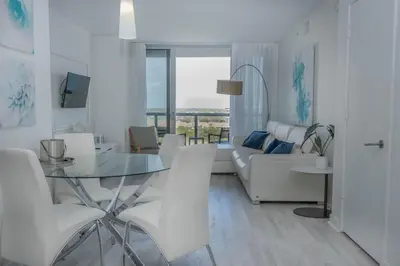 a white living room with a glass table and white chairs at 2B 2B Relax in Miami Beach and Luxury services in Hallandale Beach