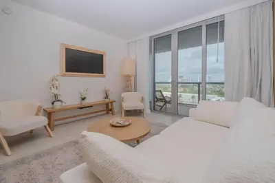 a living room with white furniture and a large window at Enjoy Miami 2B 2B pool beach and Aventura Mall in Hallandale Beach