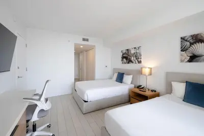 a hotel room with two beds and a desk at 2B 2B Beautiful Apt in Hallandale Beach with Beach Service 2605 in Hallandale Beach