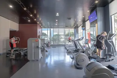 a gym with several people exercising on tread machines at Relax in Miami 2B 2B Beach and Pool with Drinks in Hallandale Beach