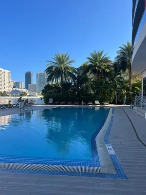 a large swimming pool with palm trees in the background at BeachWalk Studio Apmt 2 Beds with Beach Service 2103 in Hallandale Beach