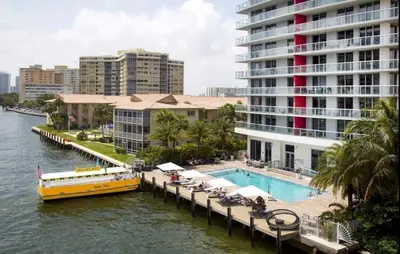 a yellow boat on a river next to a large building at BeachWalk Studio Apmt 2 Beds with Beach Service 2103 in Hallandale Beach