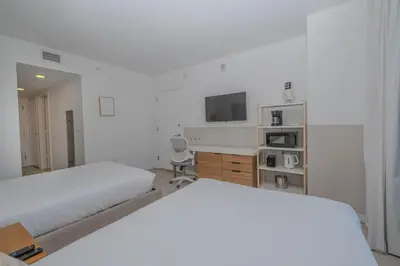 a white bedroom with two beds and a desk at Enjoy Miami Beach Pool and Restaurant 2B 2B 2007 in Hallandale Beach