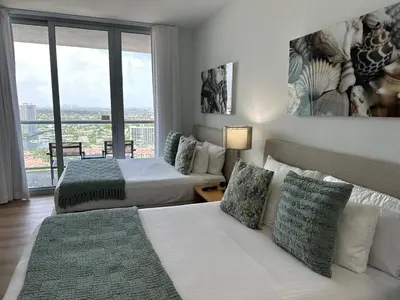 a hotel room with two beds and a large window at Studio Miami with Beach and Lounge Chairs 2 Full beds 2403 in Hallandale Beach