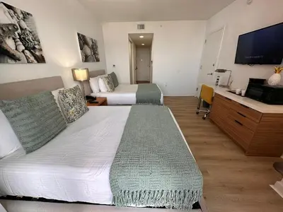 a hotel room with two beds and a flat screen tv at Studio Miami with Beach and Lounge Chairs 2 Full beds 2403 in Hallandale Beach