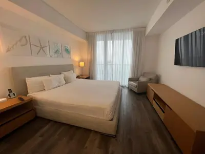 a bedroom with a large white bed and a chair at Miami Beautiful with kitchen, pool and mall Apmt 1B 1B 1408 in Hallandale Beach