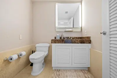 a bathroom with a toilet and a sink with a mirror at Oceanfront Ritz-Carlton 1 Bedroom Luxury Residence in Fort Lauderdale