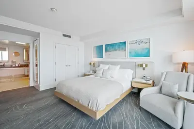 a white bedroom with a bed and a chair at Oceanfront Ritz-Carlton 1 Bedroom Luxury Residence in Fort Lauderdale