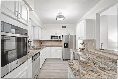 a kitchen with white cabinets and marble counter tops at Sleeps 12 Private Pool & Gameroom near Casino, Beaches & Hard Rock Stadium in Hollywood