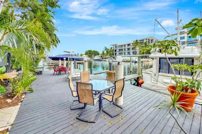 a deck with a table and chairs and a boat at Singer House on the Water in Fort Lauderdale