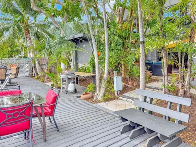 a deck with a table and chairs and a bench at Singer House on the Water in Fort Lauderdale