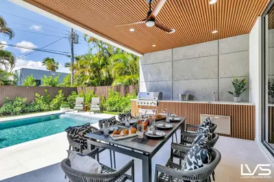 an outdoor dining area with a table and chairs next to a pool at Villa Enclave- Brand New Luxe Las Olas Beach Villa in Fort Lauderdale
