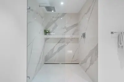 a bathroom with white marble walls and a shower at 1 Bedroom Plus Den Private Residence at Roney Palace -608 in Miami Beach