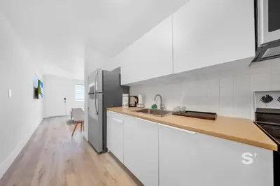 a kitchen with white cabinets and a stainless steel refrigerator at Modern Studio - Gym & Parking Close to Aventura in Miami