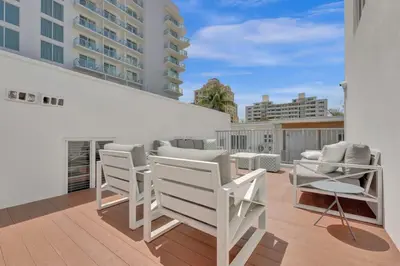 a balcony with white chairs and tables on a building at NEW Studio at Eden Collection Steps to Beach 1106 in Fort Lauderdale