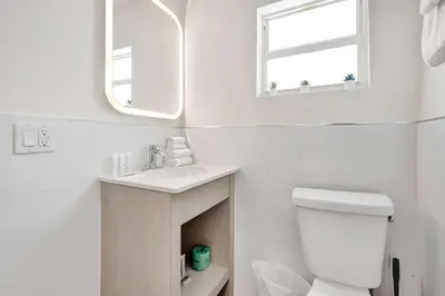 a bathroom with a toilet and a sink and a mirror at Eden Escape Walk to FLT Beach 2105 in Fort Lauderdale