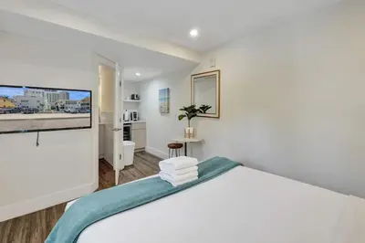 a white bedroom with a bed and a flat screen tv at Eden Escape Walk to FLT Beach 2107 in Fort Lauderdale