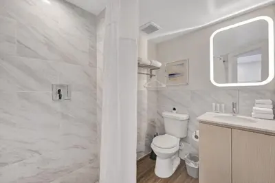 a white bathroom with a toilet and a sink at Eden Escape Walk to FLT Beach 2107 in Fort Lauderdale