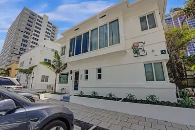 a white house with cars parked in front of it at Eden Escape Walk to FLT Beach 2204 in Fort Lauderdale