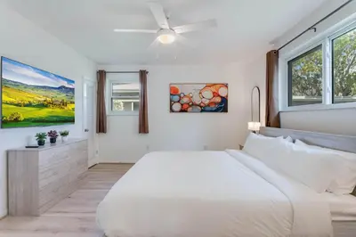 a white bedroom with a large bed and windows at Casa de Jai- your Green Space near Brickell in Miami
