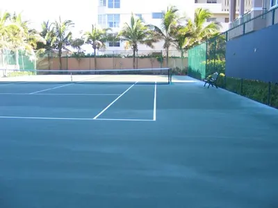 a tennis court with a person sitting on a bench on it at Beautiful Mediterranean Oceanfront Condo with Private Beach in Hallandale Beach