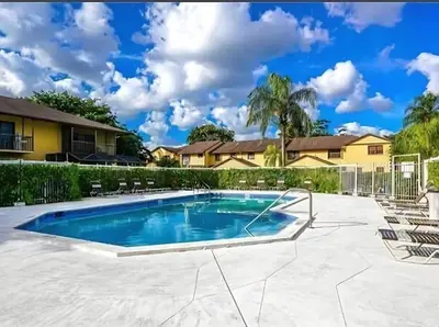a pool in a yard with chairs and a house at Spacious 4BR Miami Townhome with Communal Pool in Ives Estates