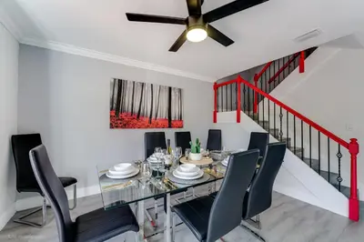 a dining room with a glass table and black chairs at Spacious 4BR Miami Townhome with Communal Pool in Ives Estates