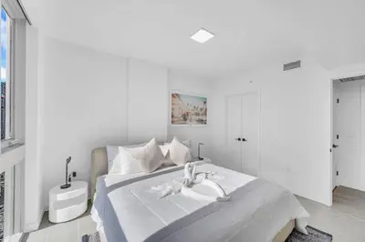 a white bedroom with a large bed with a sink at Stylish Studio and Den Across from Bayside Miami in Miami