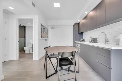a kitchen with a wooden table and a sink at Stylish Studio and Den Across from Bayside Miami in Miami