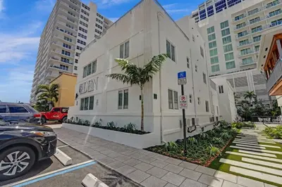 a white building with a palm tree in a parking lot at Eden Escape Studio 2103 Walk to FLT Beach in Fort Lauderdale