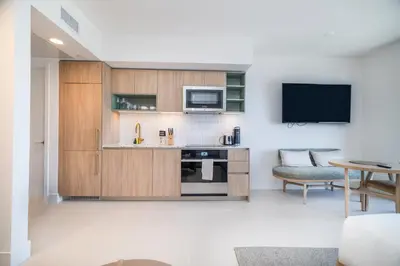 a kitchen with wooden cabinets and a tv and a table at Extraordinary Studio in Downtown Miami with incredible views in Miami