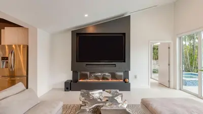 a living room with a tv above a fireplace at Luxury Waterfront Home w Pool Hot Tub Dock Near Las Olas Gulfstream in Fort Lauderdale