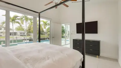 a bedroom with a large bed with a flat screen tv at Luxury Waterfront Home w Pool Hot Tub Dock Near Las Olas Gulfstream in Fort Lauderdale