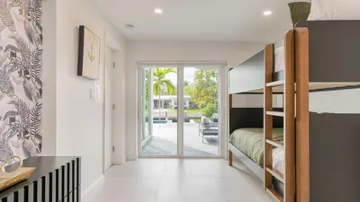 a bedroom with a bunk bed and a sliding glass door at Luxury Waterfront Home w Pool Hot Tub Dock Near Las Olas Gulfstream in Fort Lauderdale