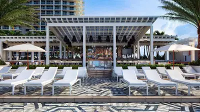 a group of white chairs and umbrellas in front of a building at Beach Club - Oceanfront Luxury, Resort Amenities, Balcony Views in Fort Lauderdale