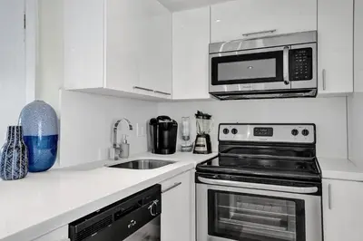 a kitchen with a microwave and a stove and a sink at Villa Monaco in Miami Beach