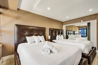 two beds in a hotel room with white sheets at Beachside Condo with Resort Amenities, Including Pools, Gym, and Bathtub 503 in Miami Beach
