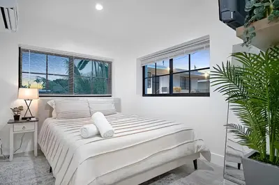 a white bedroom with a bed and two windows at Tropical Guest House at VIlla Verde Miami in Miami