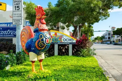 a colorful chicken statue sitting in the grass next to a sign at Modern Bedroom In Central Miami Shared with host in Miami