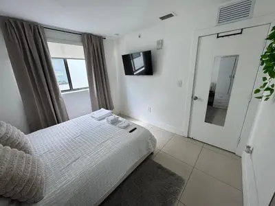 a white bedroom with a bed and a television at Modern Bedroom In Central Miami Shared with host in Miami