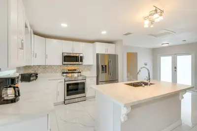 a large kitchen with white cabinets and a sink at 8 Mi to Wynwood Waterfront Retreat with Lanai in Miami
