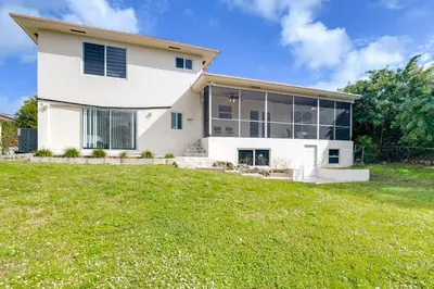 a large white house with a green yard at 8 Mi to Wynwood Waterfront Retreat with Lanai in Miami