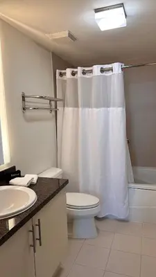 a bathroom with a white shower curtain and a toilet at Breathtaking Direct Bay Views 2 bedroom condo with parking in Miami