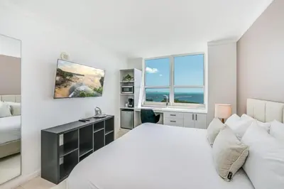 a white bedroom with a bed and a desk at Coconut Grove Bayview unit Parking Included in Miami